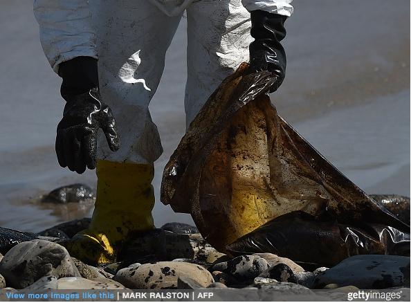 A worker cleans oil from the rocks and beach at Refugio State Beach